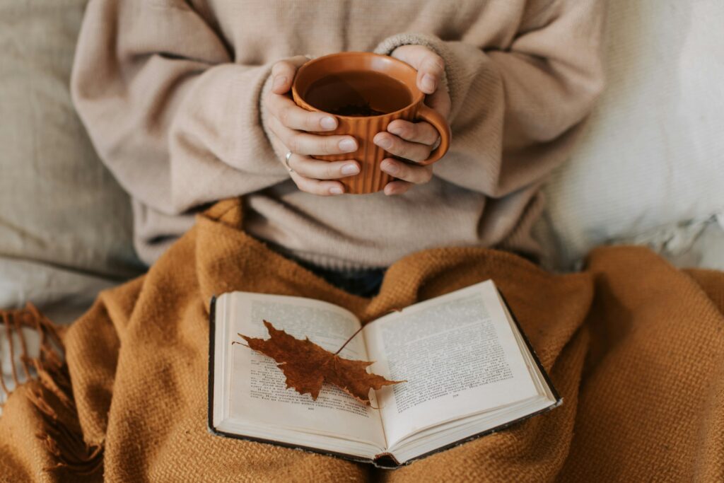 hands holding tea and a book